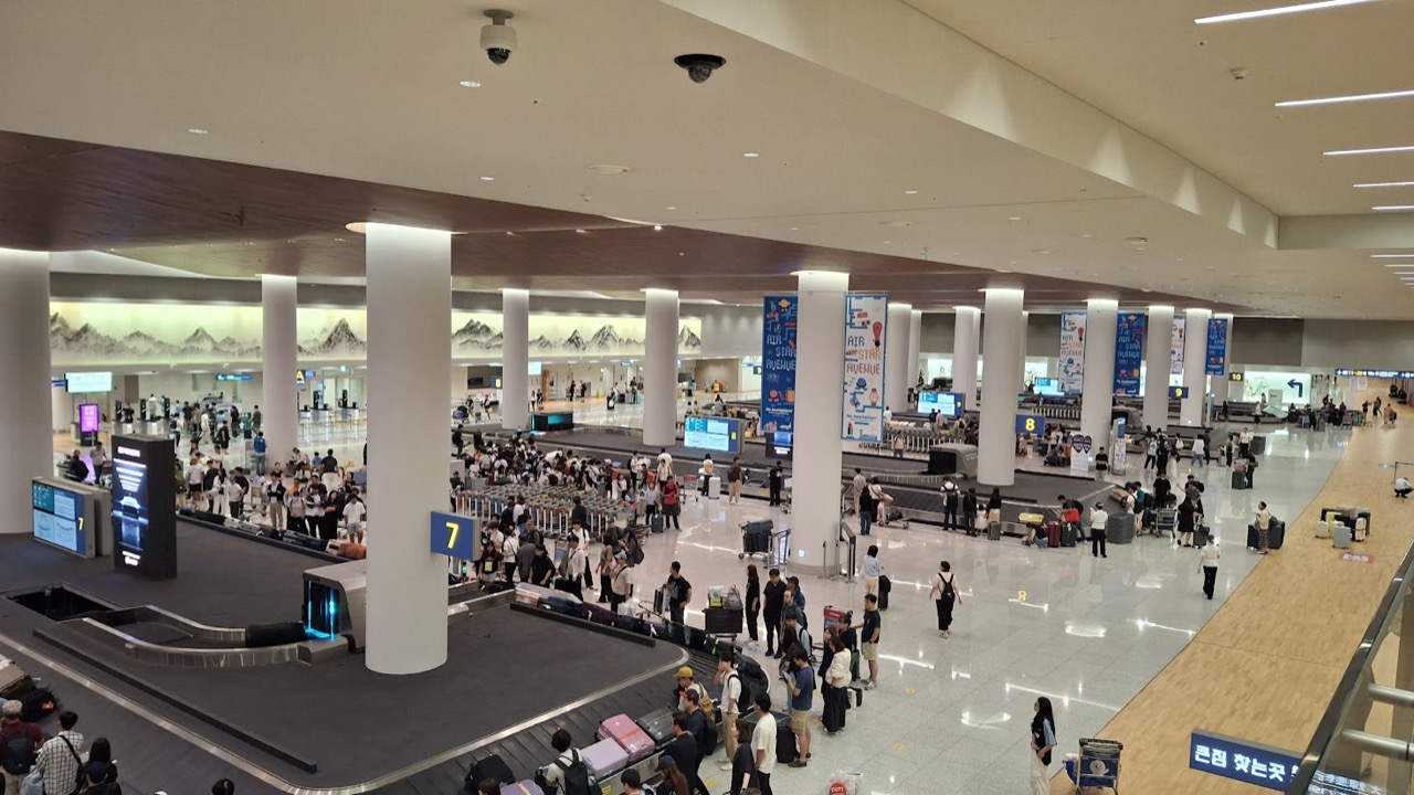 Travelers waiting beside baggage carousels in the Incheon Airport Terminal 2 arrivals hall