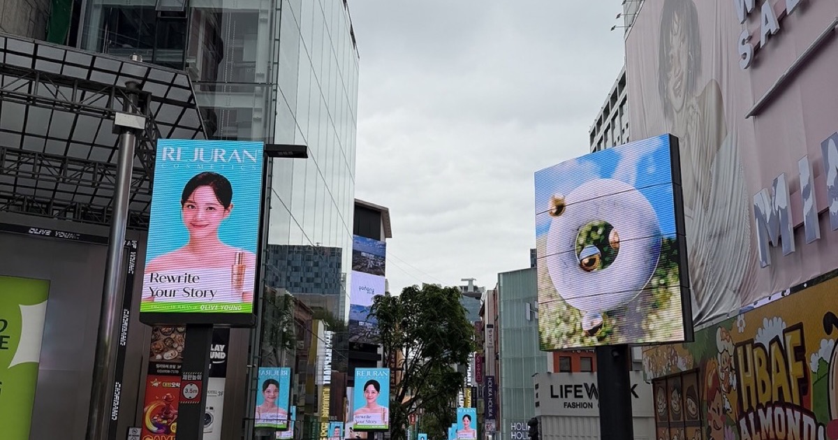 Pedestrians walking between shopfronts on a central Myeongdong shopping street