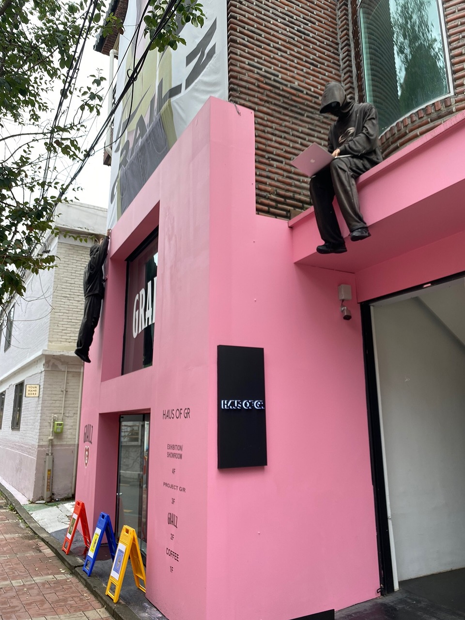Pedestrians walking past low-rise shops and a bright pink storefront in Seoul's Seongsu neighborhood